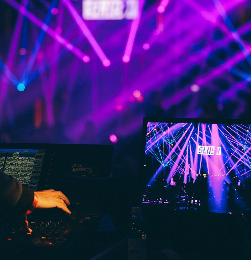 Person working at technical controller looks at computer showing laser lights at slush along with the logo of slush